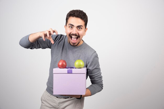 Screaming man holding a purple box with apples.