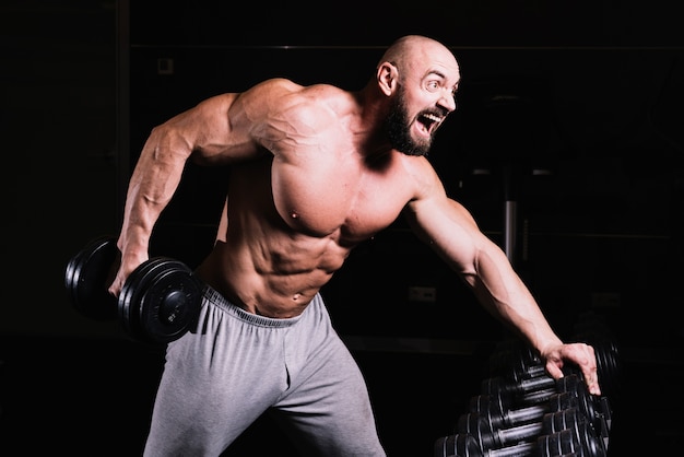 Screaming man lifting heavy dumbbell