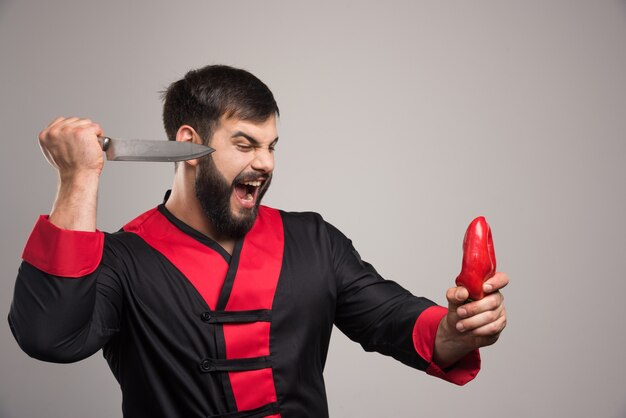 Screaming man trying to cut a red pepper.