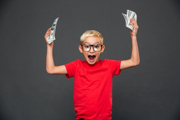 Бесплатное фото Кричать удивлен маленький мальчик, показывая деньги.