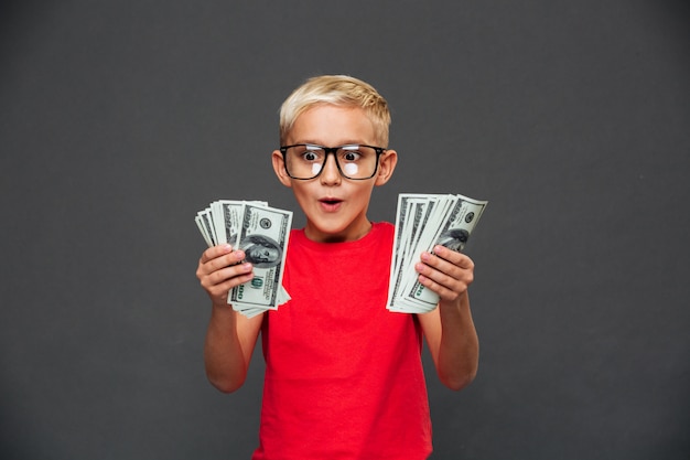 Free photo screaming surprised little boy child showing money.