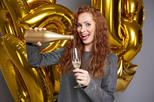 Screaming woman pouring champagne at studio shot