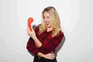 Free photo screaming woman talking by red retro telephone.