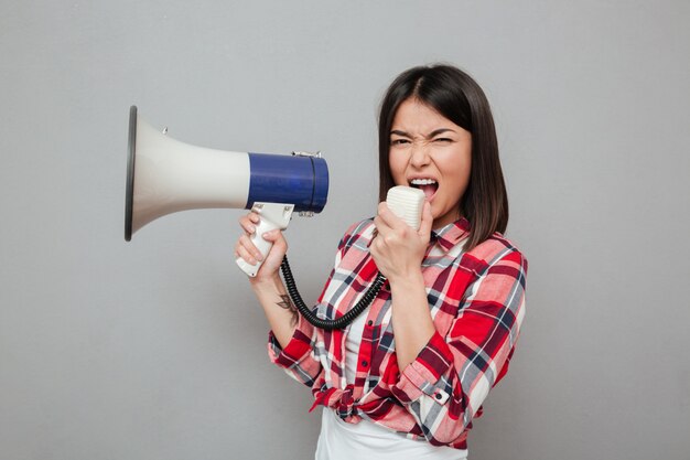Screaming young asian woman holding loudspeaker.