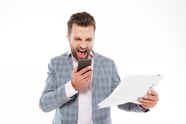 Free photo screaming young man holding gazette and talking by phone.