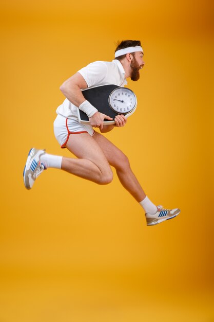 Screaming young sportsman jumping holding scales