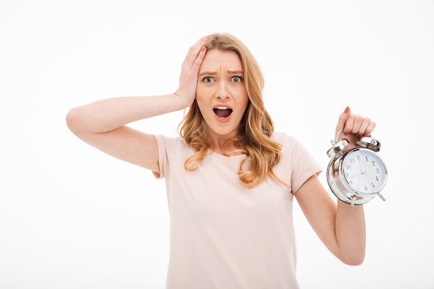 Screaming young woman holding alarm clock.