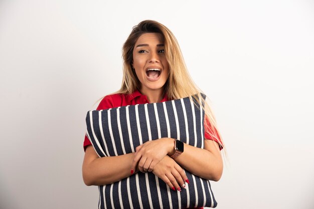 Screaming young woman hugging a pillow.