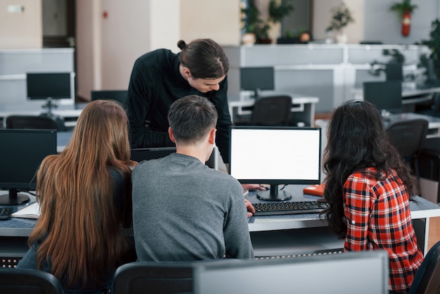 Foto gratuita schermo con colore bianco. metti lì il tuo testo. gruppo di giovani in abiti casual che lavorano nell'ufficio moderno