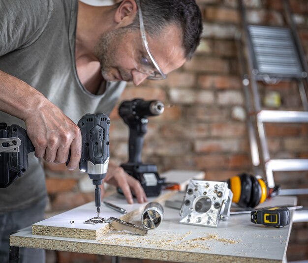 Screwing a self-tapping screw into a metal fastening hole on a wood strip using a screwdriver, the work of a carpenter.