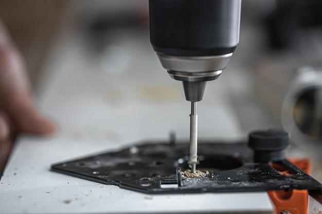 Free photo screwing a self-tapping screw into a metal fastening hole on a wood strip using a screwdriver, the work of a carpenter.