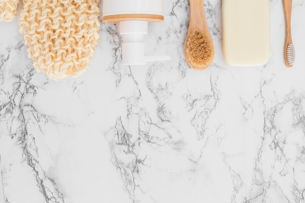 Scrub glove; cosmetic bottle; soap and brush on marble background