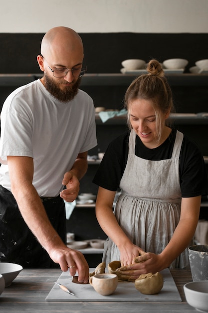 Foto gratuita coppia di scultori che lavorano insieme con l'argilla in studio