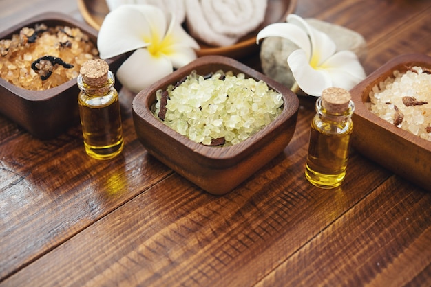 Sea salt, towels, aroma oil in bottles and flowers on vintage wooden background.