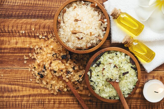 Sea salt, towels, aroma oil in bottles and flowers on vintage wooden background.