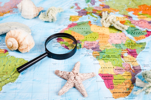 Free photo sea shells and magnifying glass on world map