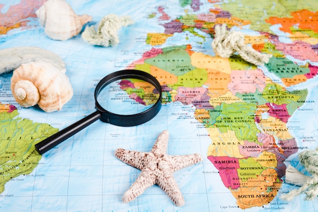 Sea shells and magnifying glass on world map