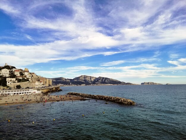 Sea surrounded by buildings and hills under a cloudy sky and sunlight in Marseille in France