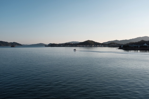 Free photo sea surrounded by hills covered in buildings and greenery under a blue sky