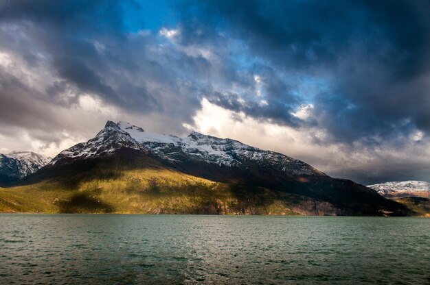 Sea surrounded by mountains under a cloudy sky in Patagonia, Chile
