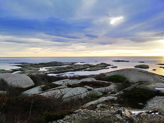 ノルウェーのラッケで日没時に曇り空の下で岩に囲まれた海