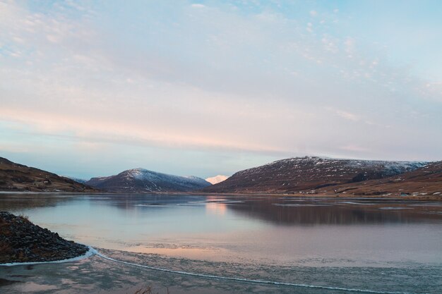 Sea surrounded by rocks covered in the snow and reflecting on the water in Iceland