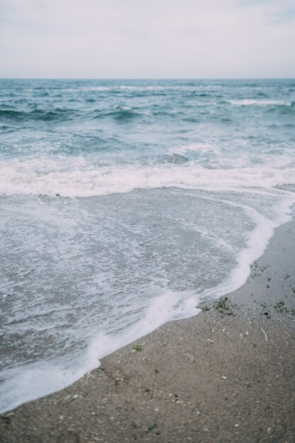 Sea with the waves crashing on to the beach creating sea spray.