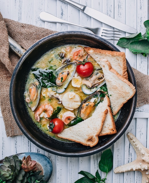 seafood in the casserole with toasts