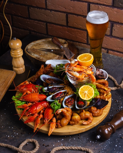 Seafood plate with shrimps, mussels, lobsters served with lemon and glass of beer