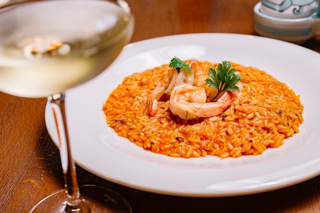 Seafood risotto with tomato sauce garnished with shrimp