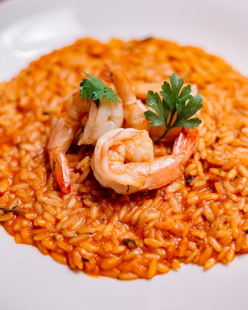 Seafood risotto with tomato sauce garnished with shrimp