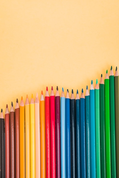 Free photo seamless colorful pencils arranged in row on yellow surface