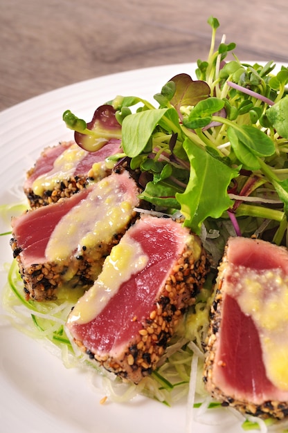 Seared tuna coated with sesame seeds with sauce close up
