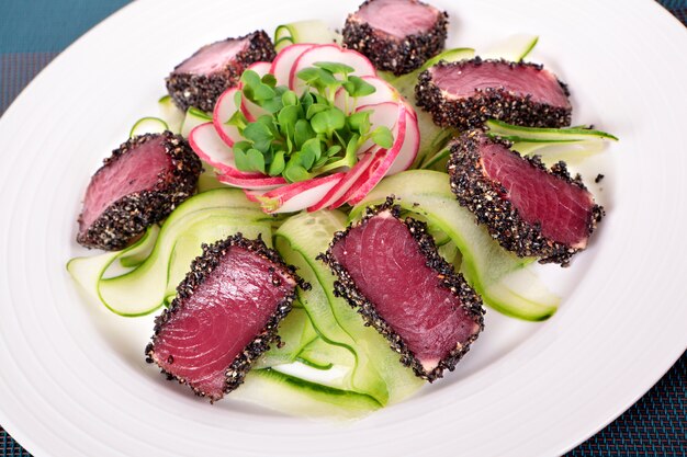 Seared tuna and green salad on white plate