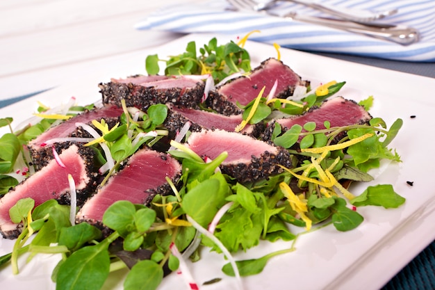 Запеченный тунец с зеленым салатом на столе