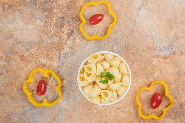 Pasta a forma di conchiglia in una ciotola con pepe e pomodori