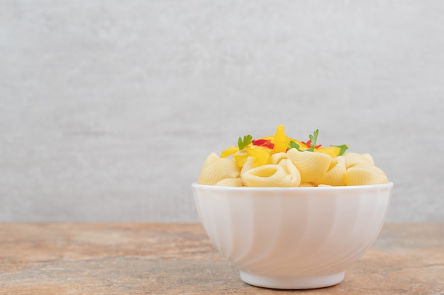 Foto gratuita pasta a forma di conchiglia con fette di verdura in una ciotola bianca