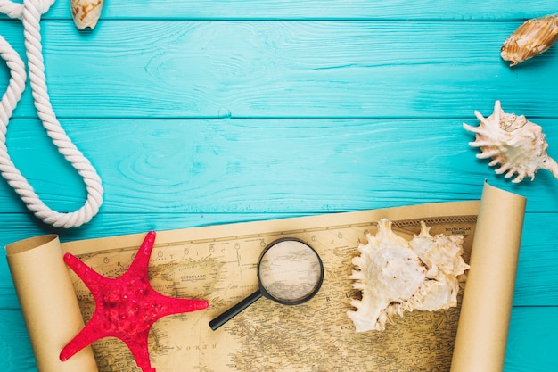 Seashells and starfish near magnifying glass on map