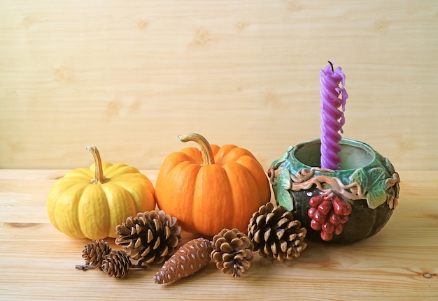 Seasonal decorations with pumpkins, pine cones and purple candle