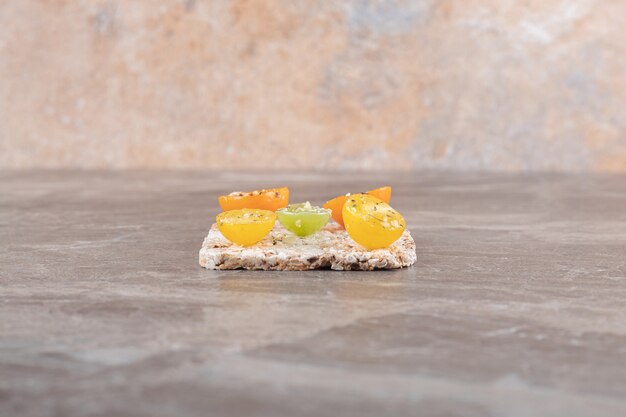 Seasoned tomato slices with rice cake underneath , on the marble surface