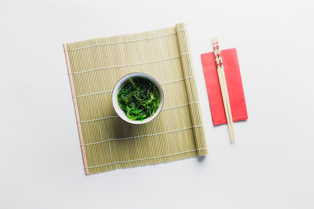 Seaweed salad and bamboo napkin near chopsticks
