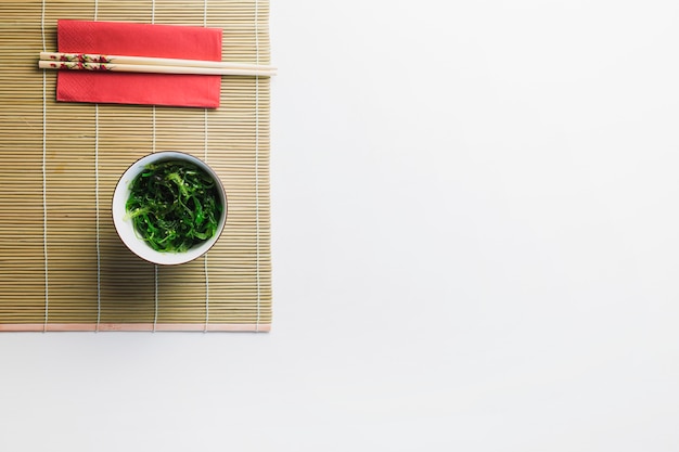Seaweed salad and chopsticks on bamboo napkin