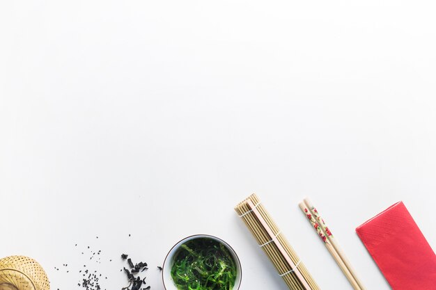 Seaweed salad near chopsticks and bamboo napkin