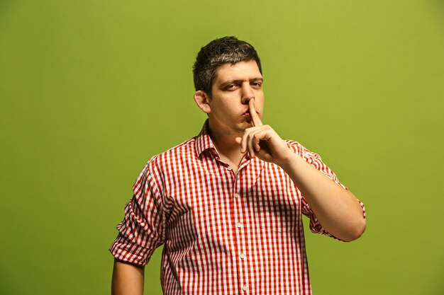 Secret, gossip concept. Young man whispering a secret behind his hand.