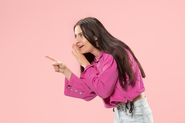 Secret, gossip concept. Young woman whispering a secret behind her hand. Business woman isolated on trendy pink studio background. Young emotional woman. Human emotions, facial expression concept.
