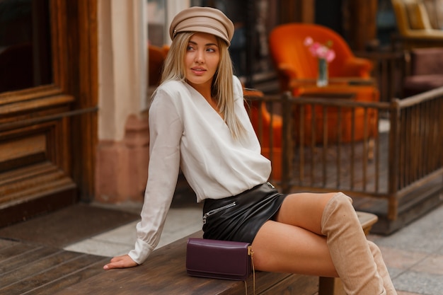 Seductive blond woman  with perfect legs sitting on bench 