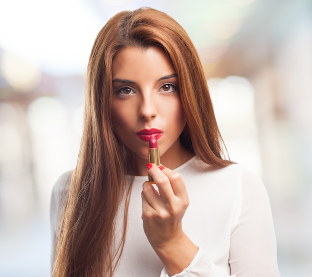 Seductive female applying red lipstick. 