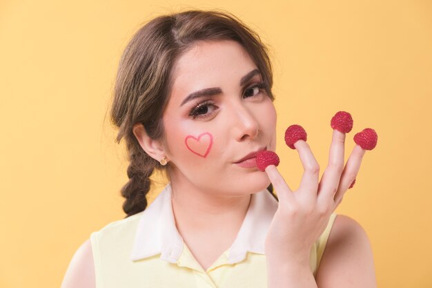 Seductive woman having raspberries on her fingertips