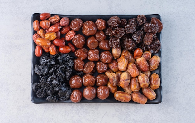 Selection of dry fruits on a platter on concrete surface.