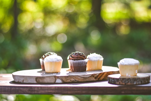 Selective closeup shot of chocolate and cream cupcakes on a wooden surface